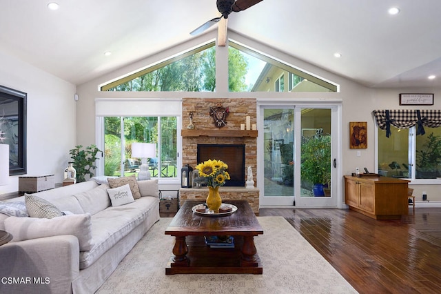 living room featuring a stone fireplace, ceiling fan, plenty of natural light, and dark hardwood / wood-style floors