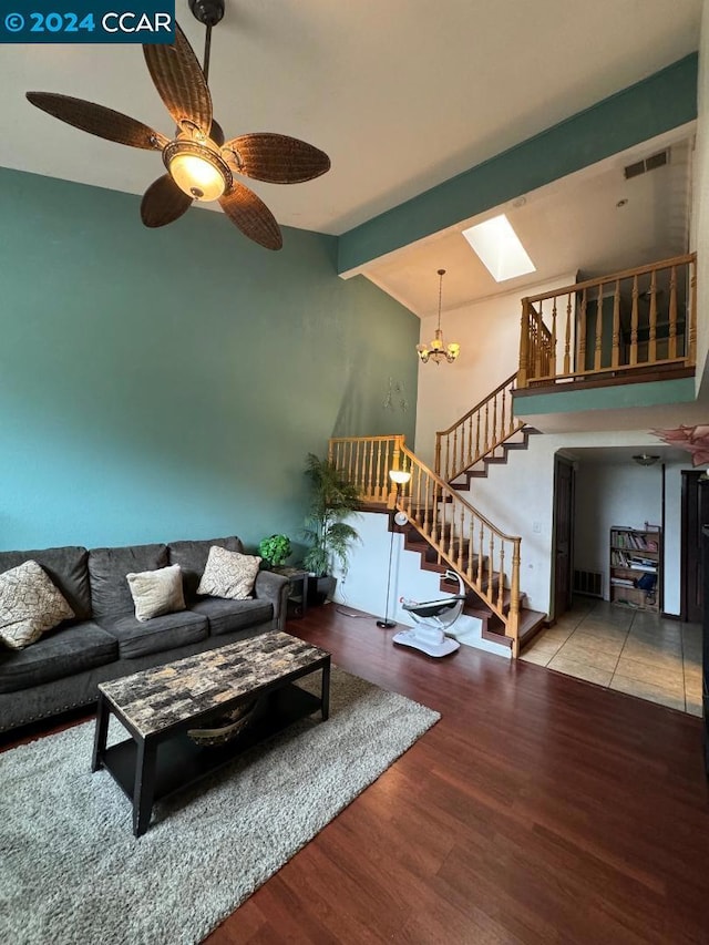 living room with ceiling fan with notable chandelier, beam ceiling, a skylight, and hardwood / wood-style flooring