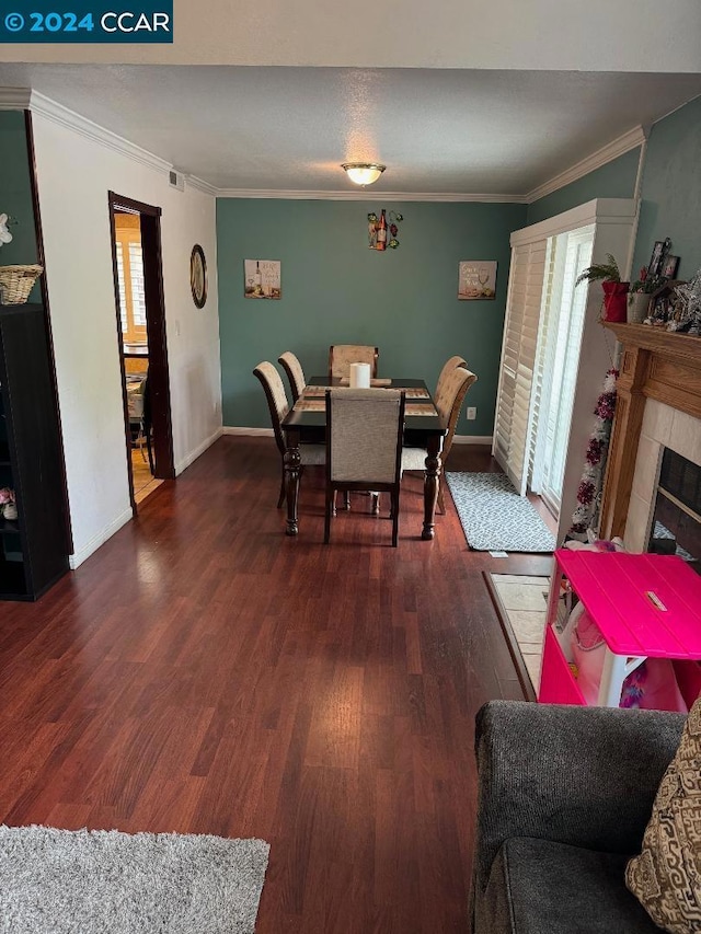 dining space with crown molding, a fireplace, dark hardwood / wood-style floors, and plenty of natural light