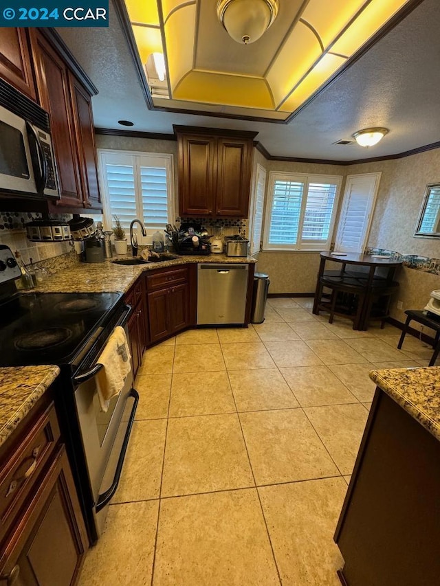 kitchen with light stone countertops, stainless steel appliances, light tile patterned flooring, and sink