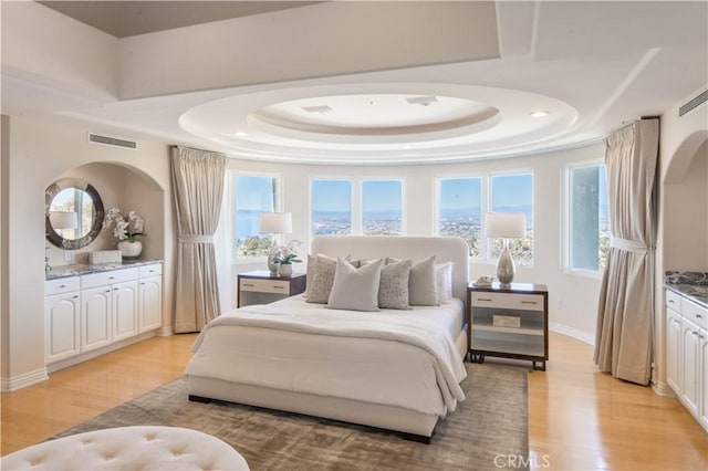 bedroom featuring light hardwood / wood-style flooring and a raised ceiling