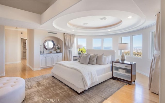 bedroom with a raised ceiling and light wood-type flooring