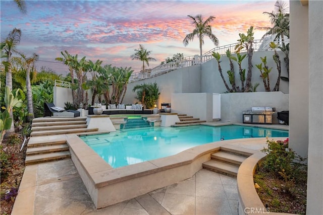 pool at dusk featuring a patio