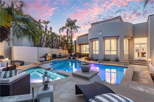 pool at dusk with french doors, an in ground hot tub, outdoor lounge area, and a patio area