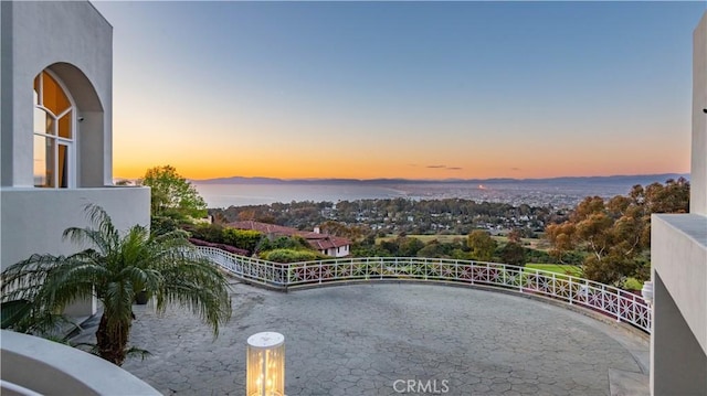 balcony at dusk with a patio and a water view