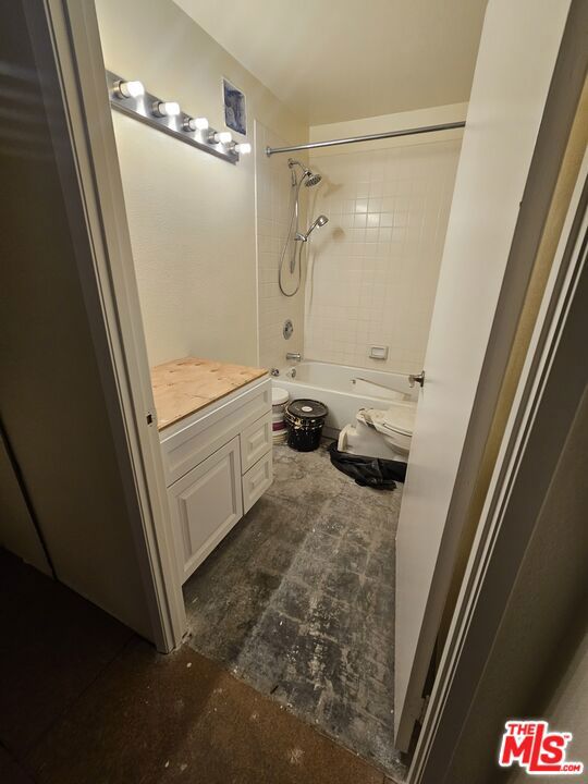 full bathroom featuring vanity, tiled shower / bath, and toilet