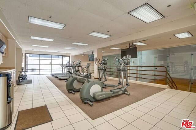 workout area featuring light tile patterned flooring and a wall of windows