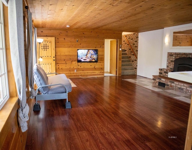 living area with hardwood / wood-style flooring, a brick fireplace, wood walls, and wood ceiling