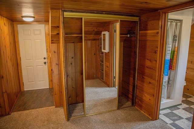 hall featuring dark carpet, wood ceiling, and wood walls