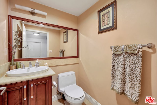 bathroom with toilet, vanity with extensive cabinet space, and tile floors