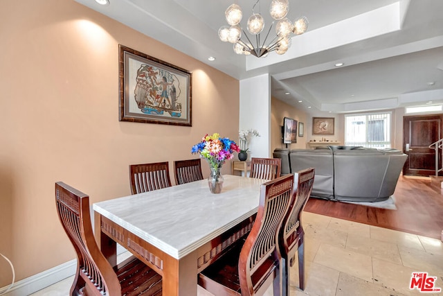 tiled dining space featuring a notable chandelier and a tray ceiling