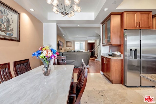 tiled dining room featuring a notable chandelier and a raised ceiling