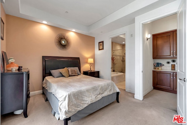 carpeted bedroom featuring a raised ceiling and ensuite bathroom