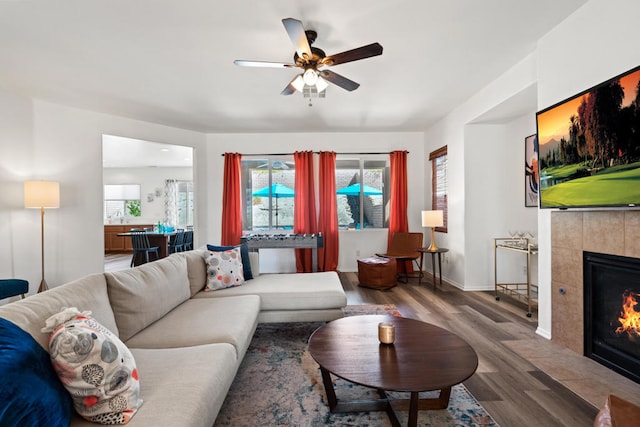 living room featuring a healthy amount of sunlight, dark hardwood / wood-style flooring, ceiling fan, and a tiled fireplace