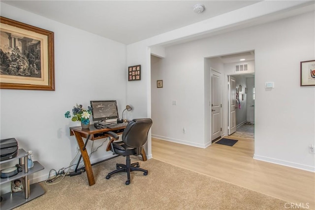 home office with light hardwood / wood-style flooring