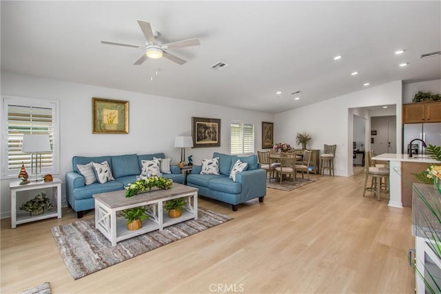 living room featuring light hardwood / wood-style flooring, ceiling fan, lofted ceiling, and sink