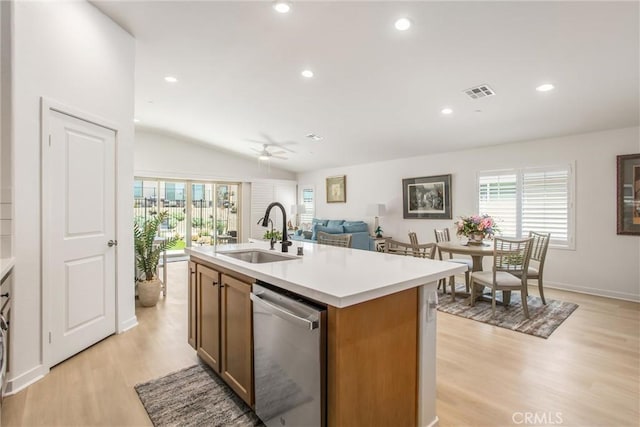 kitchen featuring vaulted ceiling, sink, a center island with sink, dishwasher, and light hardwood / wood-style floors