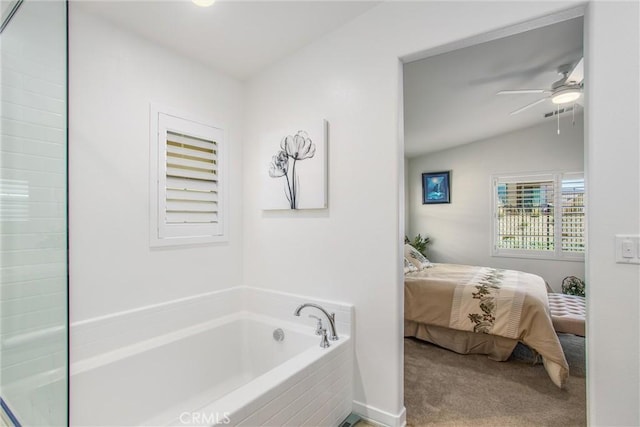 bathroom featuring tiled tub, ceiling fan, and vaulted ceiling