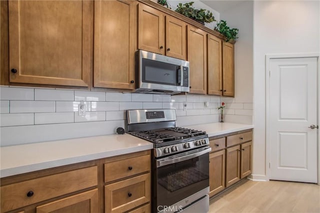 kitchen with light hardwood / wood-style floors, backsplash, and appliances with stainless steel finishes