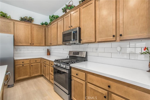 kitchen with decorative backsplash, light hardwood / wood-style floors, and appliances with stainless steel finishes