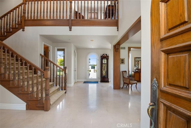 foyer with baseboards, a high ceiling, and stairway