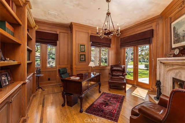 office space with a notable chandelier, plenty of natural light, light wood-style flooring, and a premium fireplace