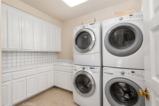 washroom with washing machine and dryer, stacked washer and clothes dryer, cabinet space, and light tile patterned flooring