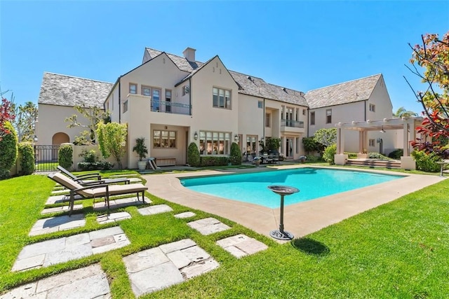 back of house featuring fence, a lawn, a fenced in pool, stucco siding, and a pergola