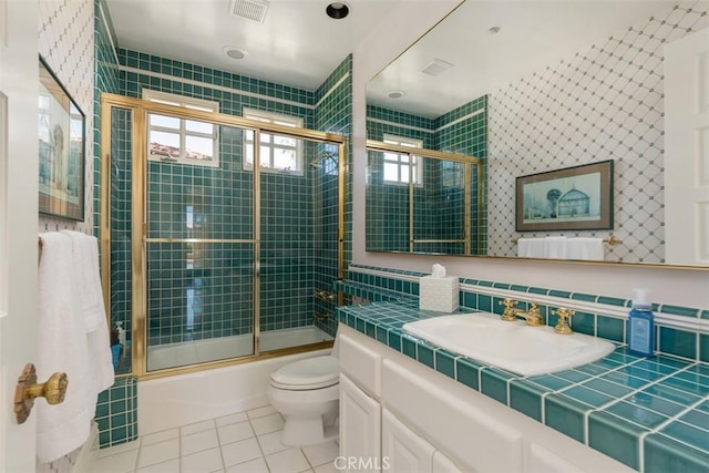 full bathroom featuring bath / shower combo with glass door, visible vents, toilet, vanity, and tile patterned floors