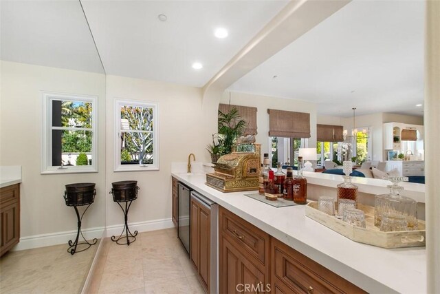 kitchen featuring light tile patterned floors, baseboards, brown cabinets, light countertops, and recessed lighting