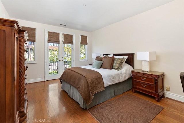 bedroom with access to outside, french doors, baseboards, and wood finished floors