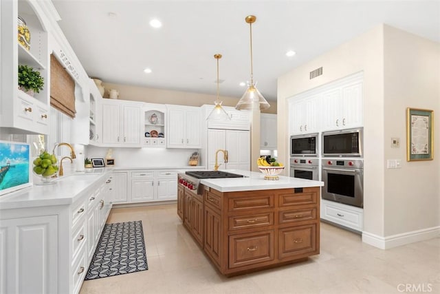 kitchen featuring open shelves, light countertops, visible vents, a sink, and built in appliances