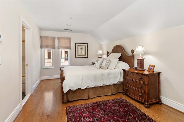 bedroom featuring light wood-type flooring, vaulted ceiling, and baseboards