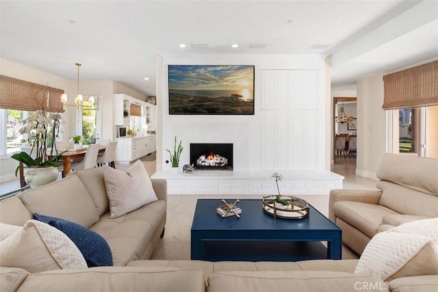 living room with a warm lit fireplace, baseboards, a chandelier, and recessed lighting