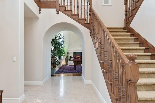 entrance foyer with stairs, marble finish floor, a high ceiling, and baseboards