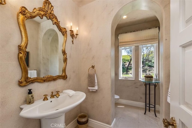 bathroom featuring toilet, baseboards, a sink, and tile patterned floors