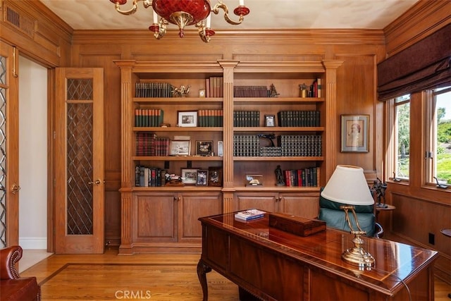 office area featuring a chandelier, built in features, wood walls, and light wood finished floors