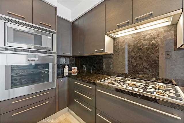 kitchen featuring appliances with stainless steel finishes, tasteful backsplash, and dark stone countertops