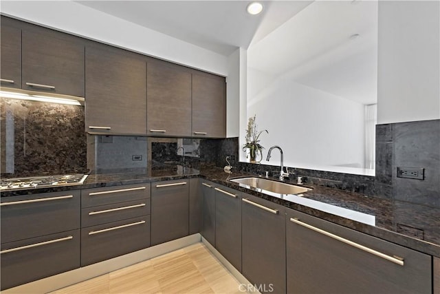 kitchen with tasteful backsplash, dark brown cabinets, extractor fan, sink, and dark stone countertops