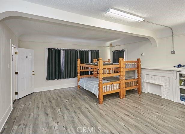 dining space with a textured ceiling, arched walkways, wood finished floors, and baseboards