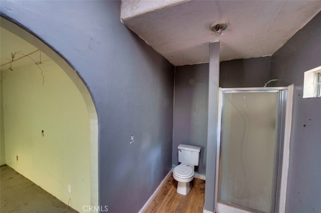 bathroom featuring a shower with door, wood-type flooring, and toilet