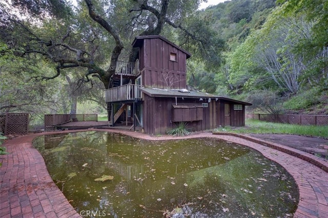 exterior space with an outbuilding, stairway, fence, a barn, and a view of trees