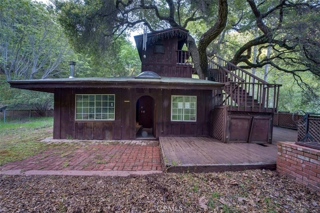 view of front facade with stairway, board and batten siding, and fence