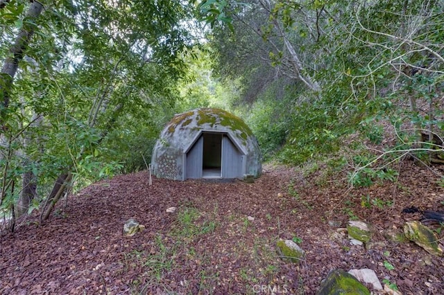 entry to storm shelter with an outbuilding and a shed