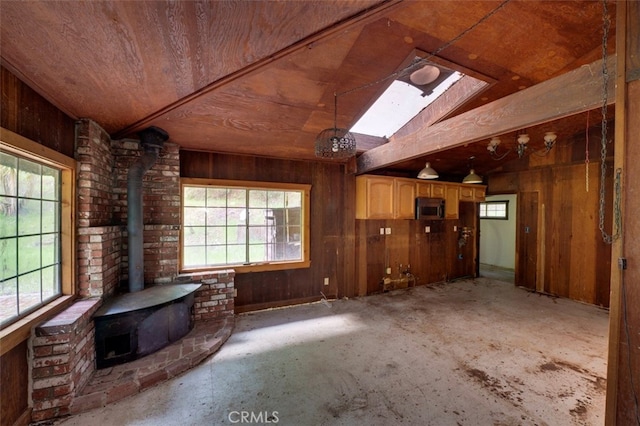 interior space featuring brick wall, wooden walls, a wood stove, and lofted ceiling with skylight