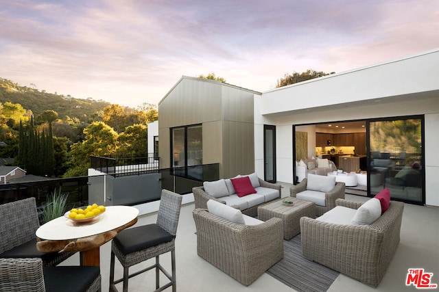 patio terrace at dusk with a balcony and an outdoor hangout area