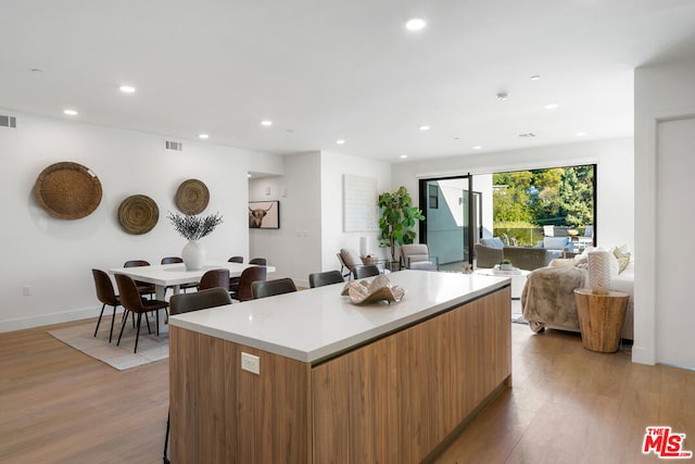 kitchen featuring a barn door, a breakfast bar, a kitchen island, and light wood-type flooring