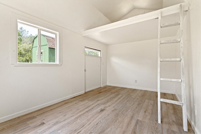 empty room with lofted ceiling and light hardwood / wood-style floors