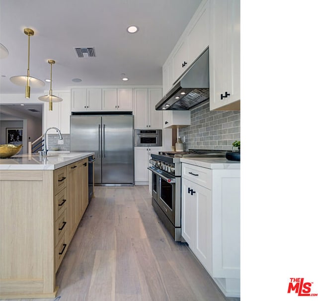 kitchen with hanging light fixtures, backsplash, light hardwood / wood-style floors, white cabinets, and high quality appliances