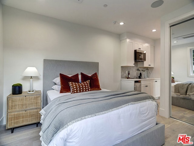 bedroom with sink and light hardwood / wood-style flooring